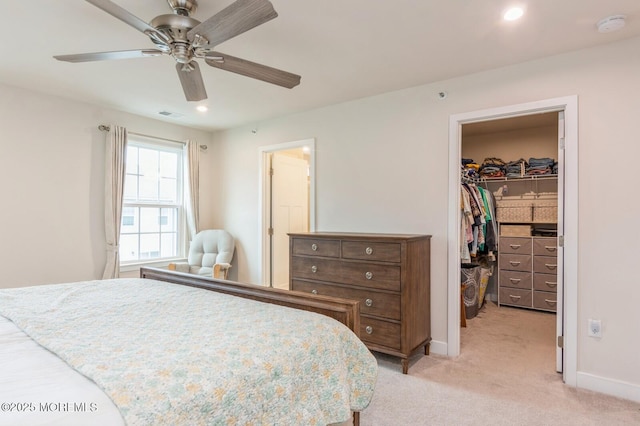 bedroom featuring visible vents, baseboards, a closet, a walk in closet, and light colored carpet