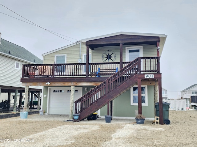 back of property featuring stairway, an attached garage, and dirt driveway