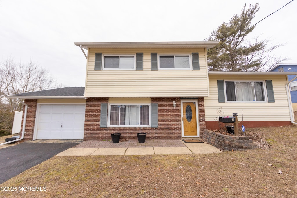 tri-level home with brick siding, driveway, and an attached garage