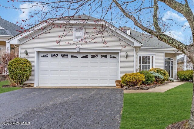view of front of home with a front lawn, an attached garage, and driveway