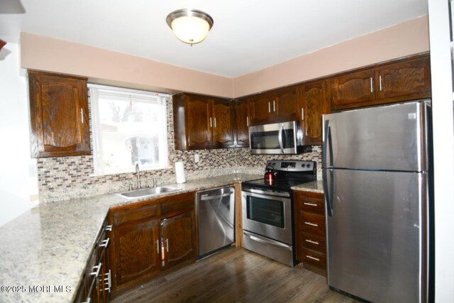 kitchen featuring a sink, stainless steel appliances, dark wood-type flooring, and backsplash