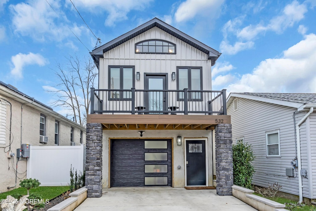 view of front facade featuring stone siding, fence, board and batten siding, concrete driveway, and an attached garage