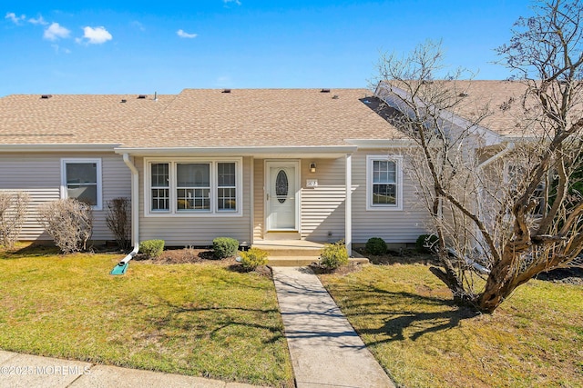 ranch-style home with roof with shingles and a front lawn
