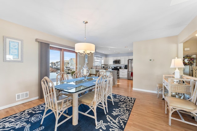 dining area with baseboards, light wood-style flooring, visible vents, and a notable chandelier