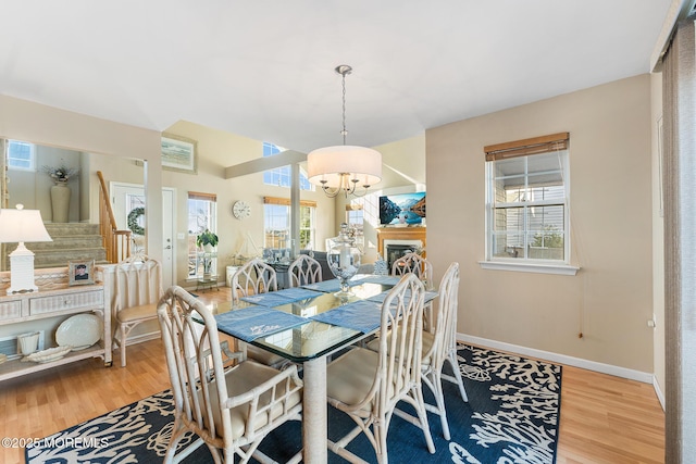 dining area featuring baseboards, an inviting chandelier, wood finished floors, and stairs