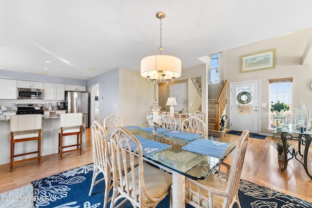dining space featuring a chandelier, light wood-style floors, stairs, and recessed lighting