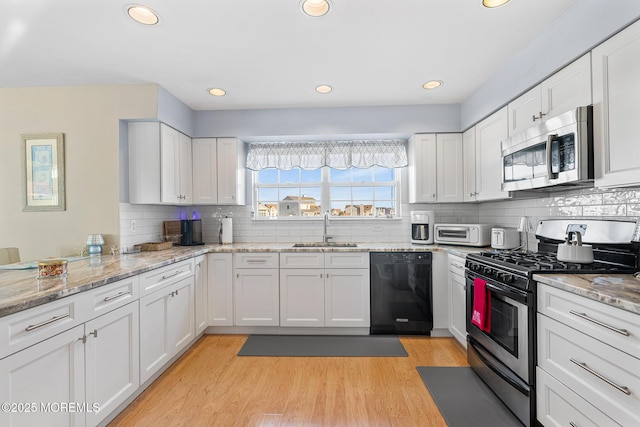 kitchen featuring white cabinetry, decorative backsplash, stainless steel appliances, and a sink