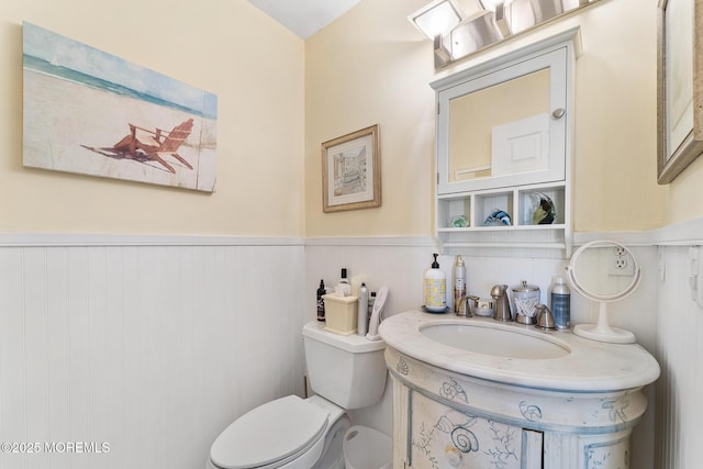 bathroom with toilet, vanity, and wainscoting