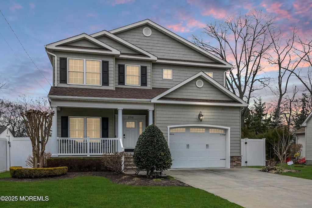 view of front of property with a garage, covered porch, driveway, and fence
