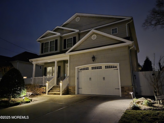 view of front of house with a porch, stone siding, a garage, and driveway