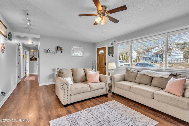 living area featuring baseboards, a textured ceiling, visible vents, a ceiling fan, and wood finished floors