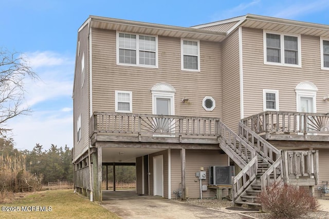 view of front of property with stairway, driveway, a wooden deck, central AC, and a carport