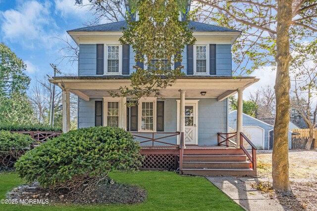 american foursquare style home with an outdoor structure, roof with shingles, a front lawn, a porch, and a garage