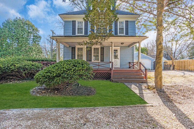 traditional style home featuring covered porch, an outdoor structure, fence, and a front lawn