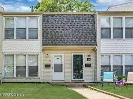 multi unit property featuring a shingled roof and a front lawn