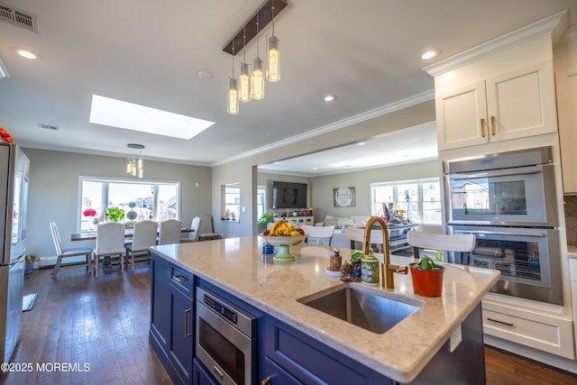 kitchen featuring blue cabinetry, visible vents, a sink, a skylight, and appliances with stainless steel finishes