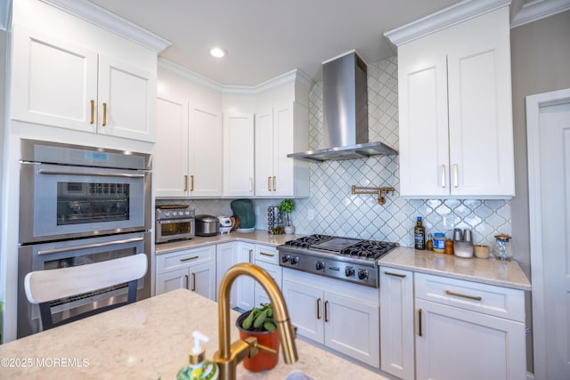kitchen featuring decorative backsplash, white cabinets, wall chimney exhaust hood, appliances with stainless steel finishes, and light stone countertops