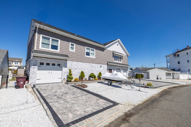 view of front of home featuring driveway, stone siding, a residential view, and a garage