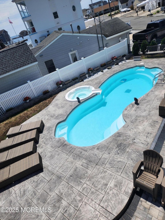 view of swimming pool featuring a patio area, a pool with connected hot tub, and a fenced backyard