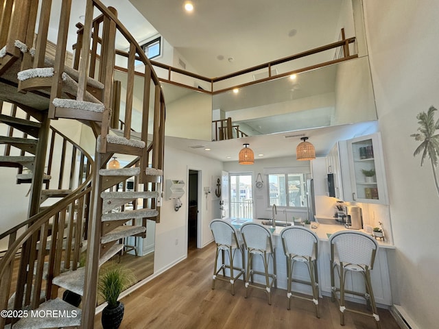 1919 Bay Blvd Unit B37, Seaside Heights, NJ 08751 - kitchen featuring a kitchen breakfast bar, white cabinetry, a baseboard heating unit, wood finished floors, and high vaulted ceiling