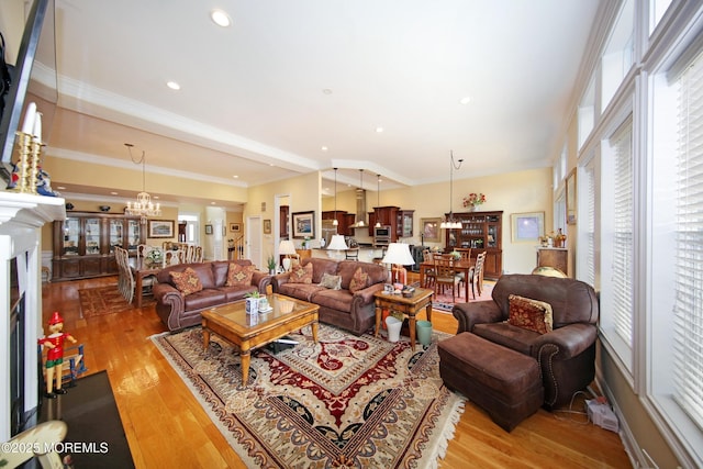 26 Aspen Ln, Tinton Falls, NJ 07724 - living area with light wood-type flooring, an inviting chandelier, ornamental molding, and a fireplace