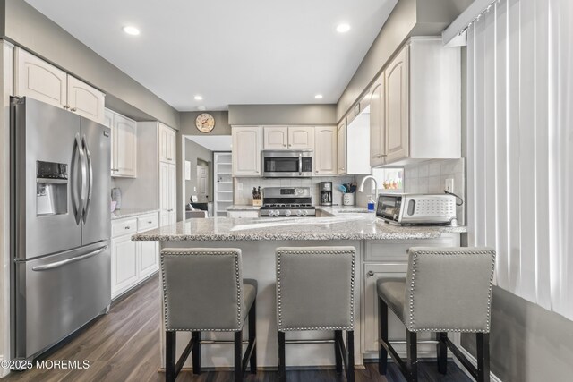 4 Whitman Rd, Morganville, NJ 07751 - kitchen featuring decorative backsplash, a peninsula, appliances with stainless steel finishes, and a sink