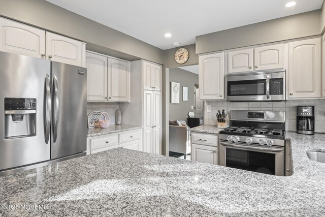 4 Whitman Rd, Morganville, NJ 07751 - kitchen featuring light stone counters, decorative backsplash, white cabinets, and appliances with stainless steel finishes