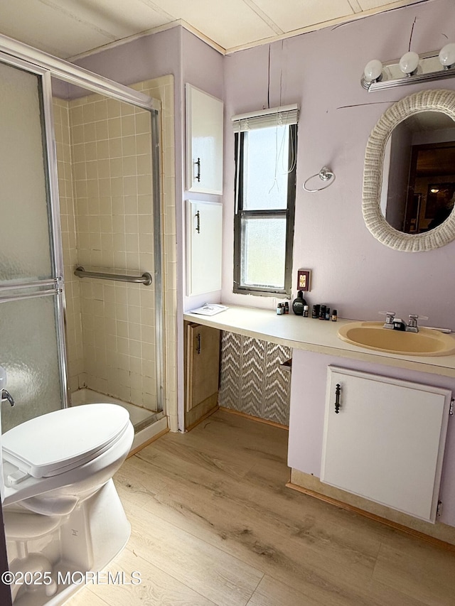 full bath with a shower stall, wood finished floors, toilet, and vanity