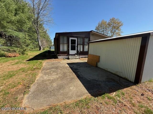 rear view of property featuring entry steps and a lawn