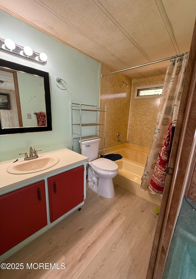 full bathroom with wood finished floors, toilet, vanity, shower / tub combo, and a textured ceiling