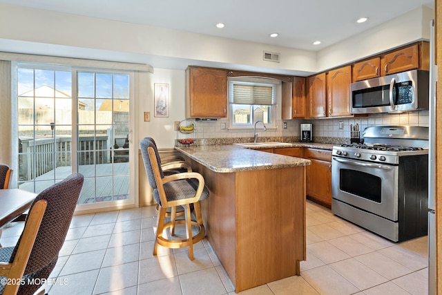 1107 Frontage Rd, Toms River, NJ 08753 - kitchen with visible vents, brown cabinets, a sink, appliances with stainless steel finishes, and a peninsula