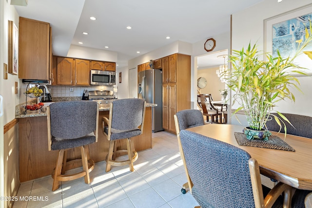 1107 Frontage Rd, Toms River, NJ 08753 - kitchen with tasteful backsplash, light stone counters, brown cabinets, a peninsula, and stainless steel appliances