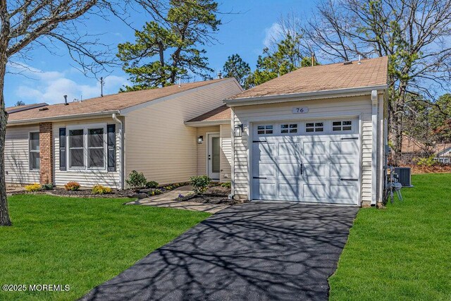 ranch-style home featuring a front yard, a garage, and driveway