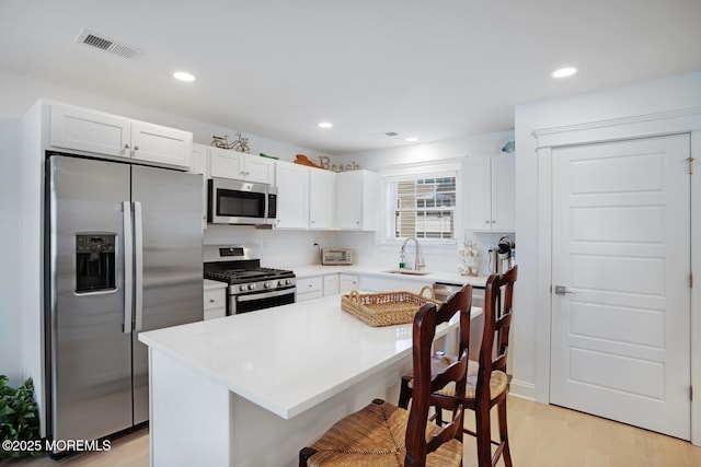 30 Elder St, Mantoloking, NJ 08738 - kitchen featuring appliances with stainless steel finishes, a breakfast bar area, light wood-type flooring, white cabinets, and a sink