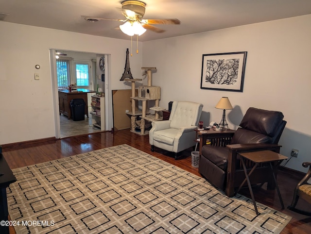 living area featuring visible vents, baseboards, ceiling fan, and wood finished floors