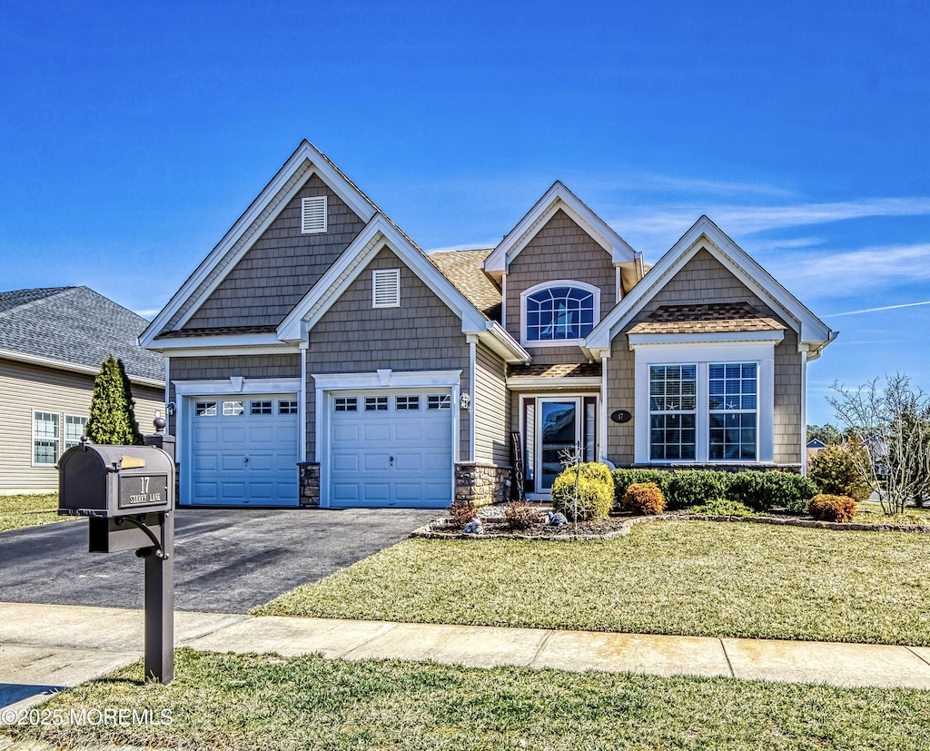 view of front of home with aphalt driveway, an attached garage, a front lawn, and stone siding