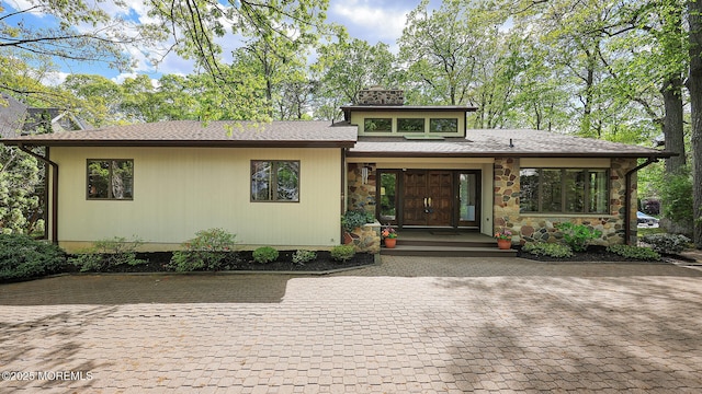 view of front of home with a chimney and stone siding