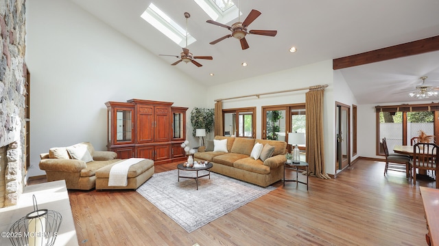 living area featuring a ceiling fan, plenty of natural light, light wood finished floors, high vaulted ceiling, and beam ceiling