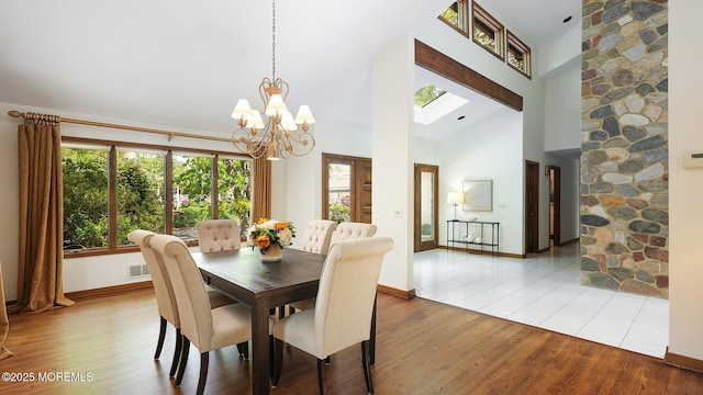dining area featuring a chandelier, wood finished floors, high vaulted ceiling, and baseboards