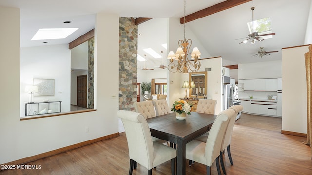 dining space featuring a skylight, high vaulted ceiling, beamed ceiling, light wood-style flooring, and baseboards