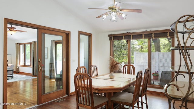 dining space featuring ceiling fan, vaulted ceiling, plenty of natural light, and dark wood-style flooring