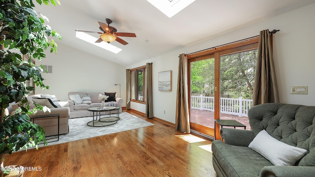 living area with a skylight, ceiling fan, vaulted ceiling, and wood finished floors
