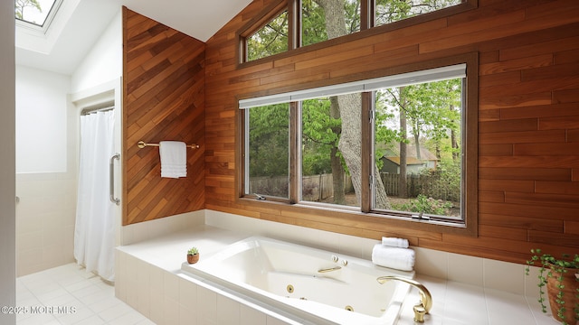 full bathroom featuring a skylight, lofted ceiling, a tub with jets, wood walls, and a shower with curtain