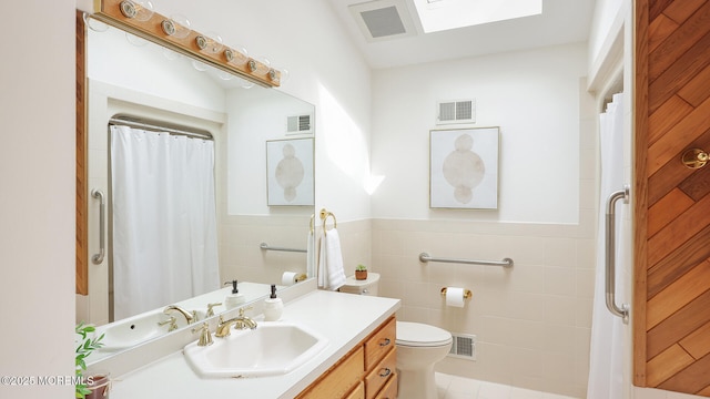bathroom with tile walls, toilet, wainscoting, vanity, and a shower with shower curtain