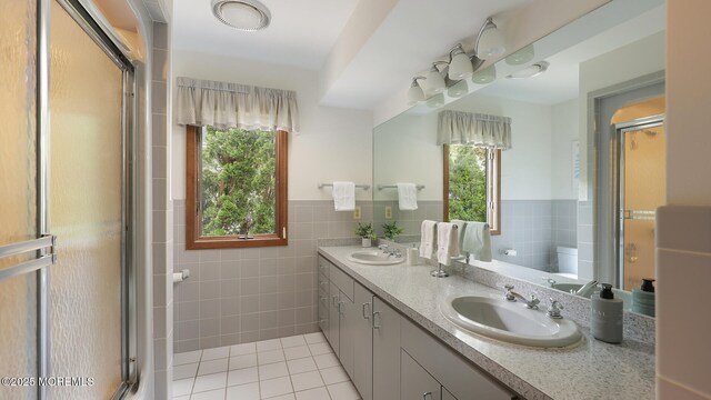 full bathroom featuring plenty of natural light, tile walls, tile patterned flooring, a shower stall, and double vanity