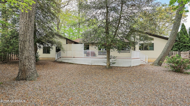 rear view of house featuring fence and a deck