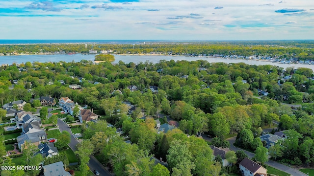 drone / aerial view of a nearby body of water and a heavily wooded area