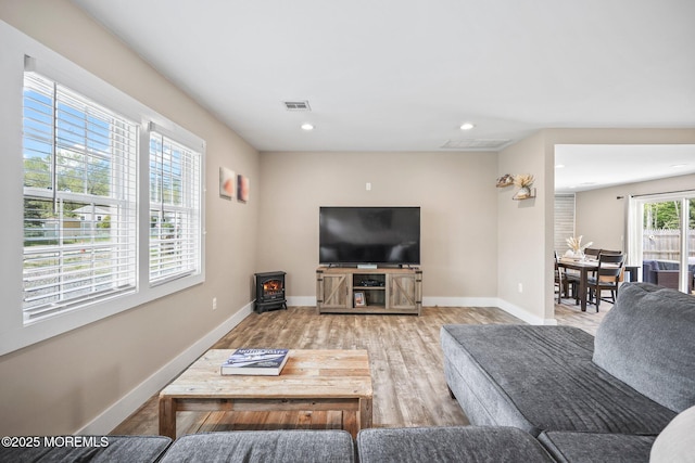 living area with a wood stove, wood finished floors, baseboards, and recessed lighting