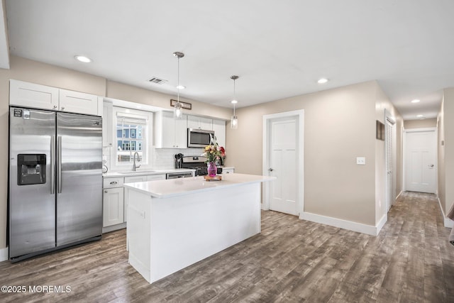 kitchen featuring appliances with stainless steel finishes, a sink, dark wood finished floors, a center island, and recessed lighting