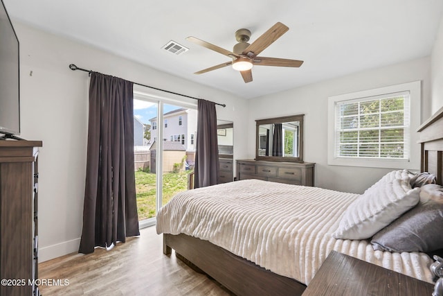 bedroom with multiple windows, wood finished floors, a fireplace, and baseboards